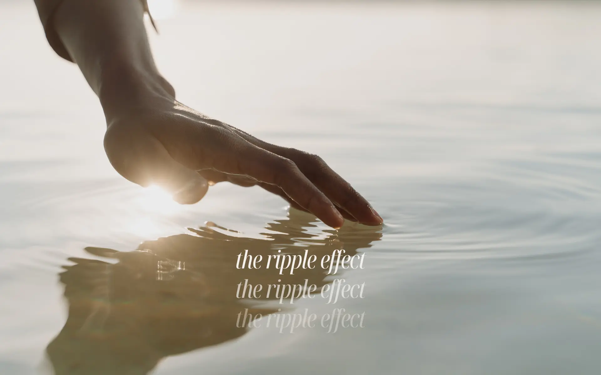 A hand touching the surface of water, creating gentle ripple circles